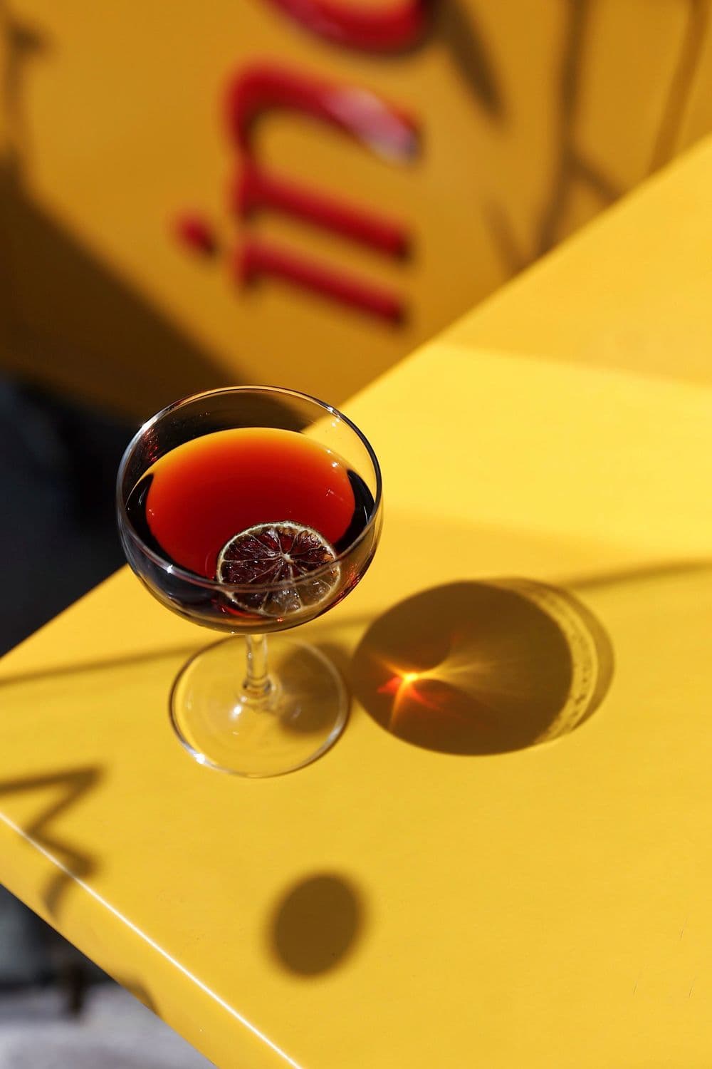 A red cocktail on a yellow Indico table